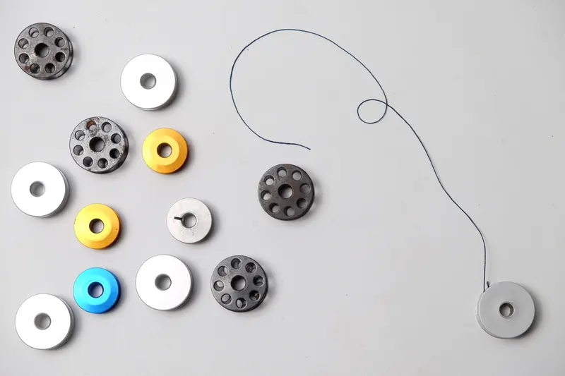 Collection of colorful sewing bobbins with thread on a white background, ideal for crafting themes