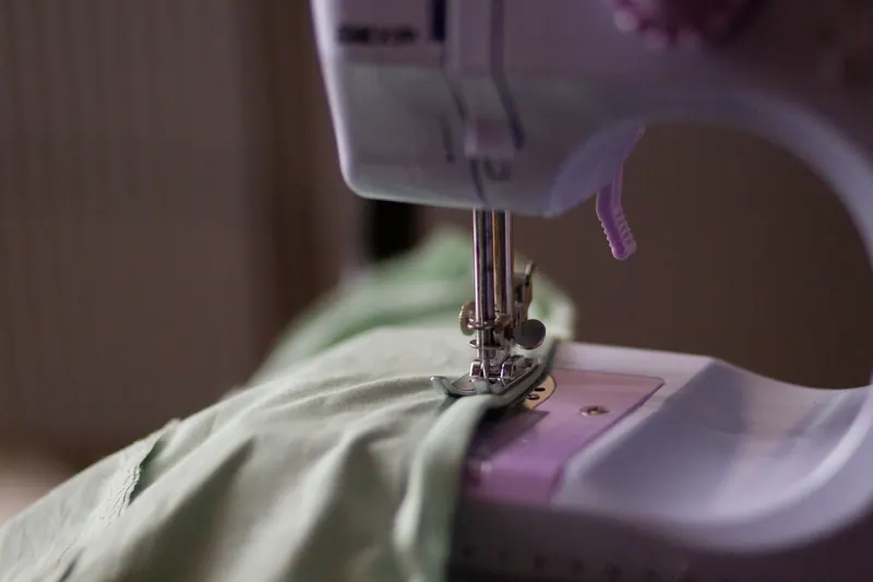 Detailed view of a sewing machine needle stitching green fabric