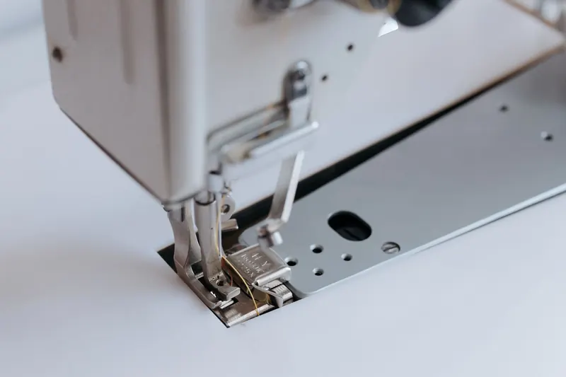 Detailed view of a sewing machine with focus on the needle and presser foot, showcasing precision tools