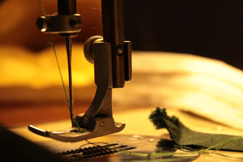 Detailed view of a sewing machine needle stitching fabric, highlighting craftsmanship