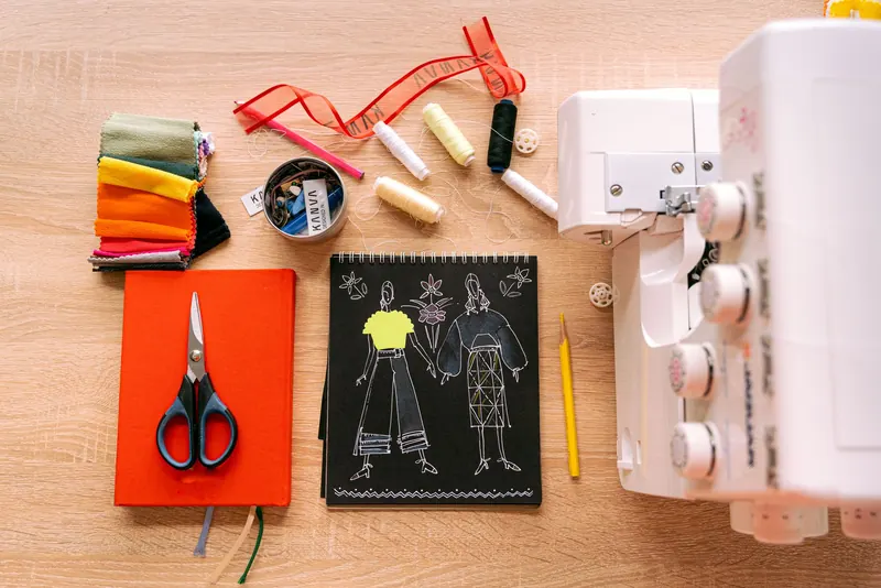 A vibrant sewing workspace featuring a sewing machine, fabrics, and design sketches on a wooden table