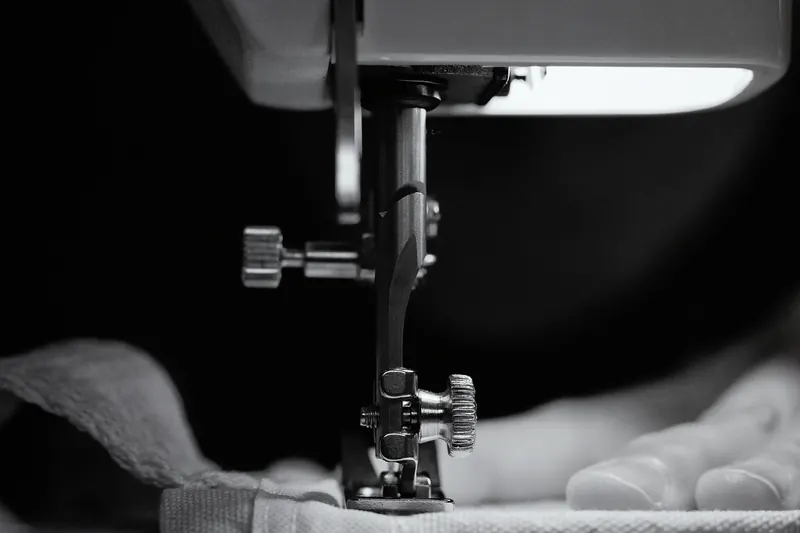 Detailed grayscale image of a sewing machine needle threading fabric, showcasing craftsmanship