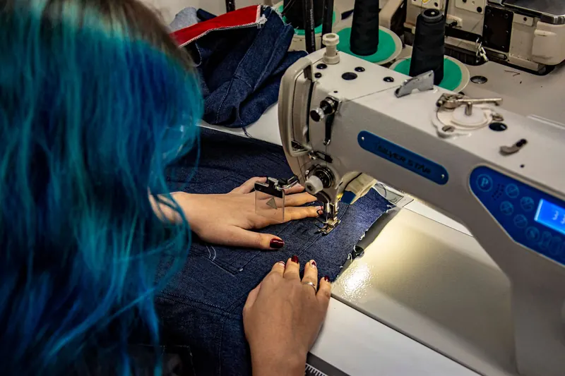 Hands sewing denim on a machine in Apucarana, Brazil. Detailed shot of skilled textile craftsmanship