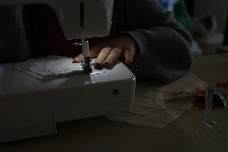 A person sewing fabric using a sewing machine, highlighting DIY and craftsmanship