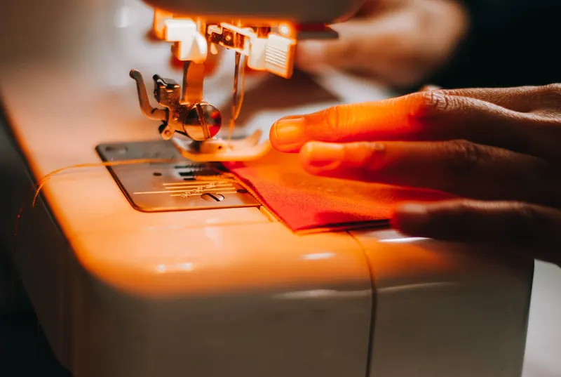 A focused shot of a sewing machine operating with fabric and hand interaction