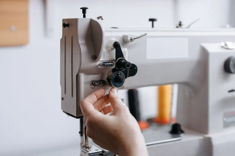 Detailed view of a hand operating a sewing machine with fine thread