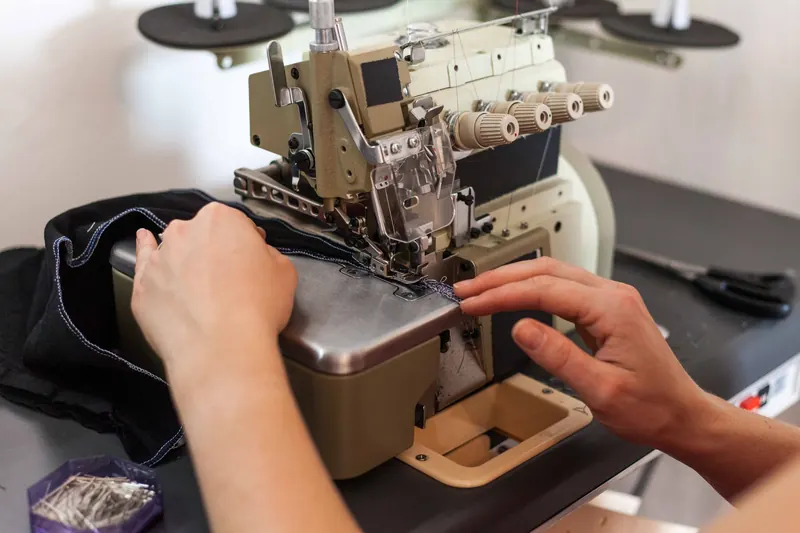 Close-up of hands sewing fabric with a professional sewing machine in a fashion studio