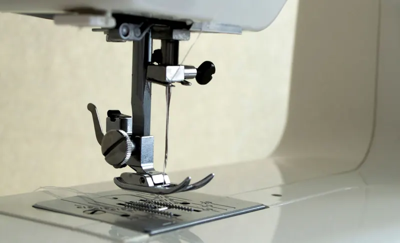 Detailed view of sewing machine foot and needle, showcasing precision engineering