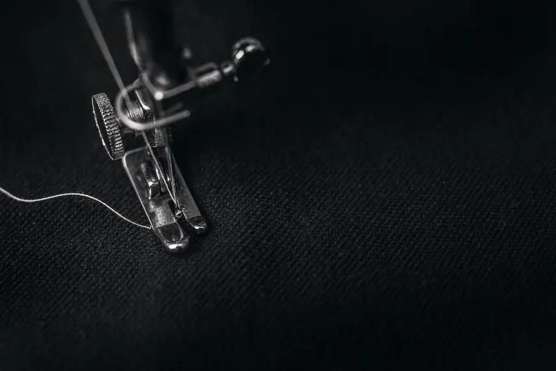 Detailed view of a sewing machine needle stitching fabric, highlighting sewing process and textile technology