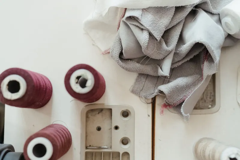 Flat lay of sewing materials including spools of thread and fabric on a workbench, ideal for crafting and textile themes