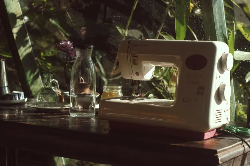 A vintage sewing machine on a wooden table with natural light streaming through a window