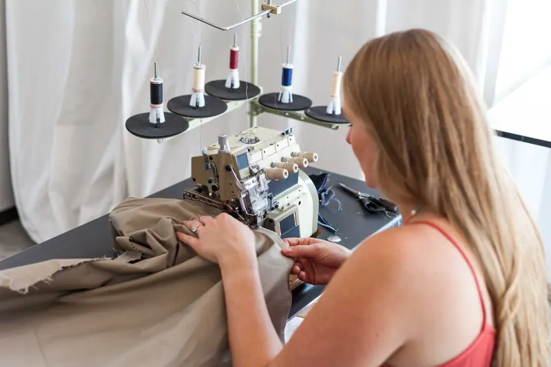 A woman sewing fabric using a sewing machine in a studio setting