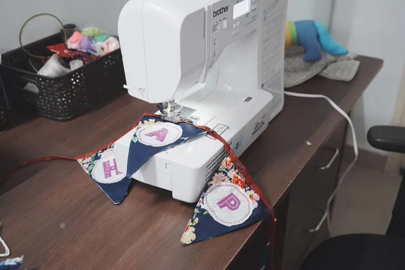 A sewing machine creates vibrant DIY bunting indoors, capturing the crafting process